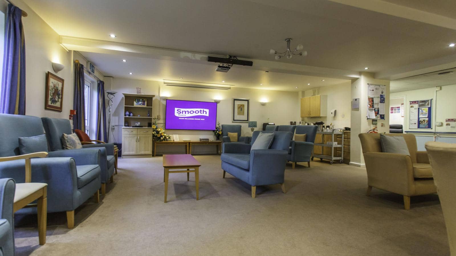 MHA Bradley Court care home living area with large TV and small kitchen