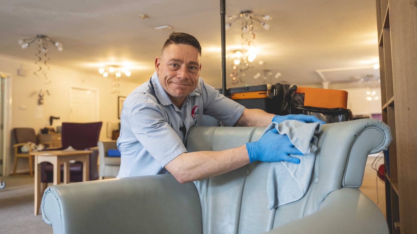 A care home worker cleaning a chair in a communal area