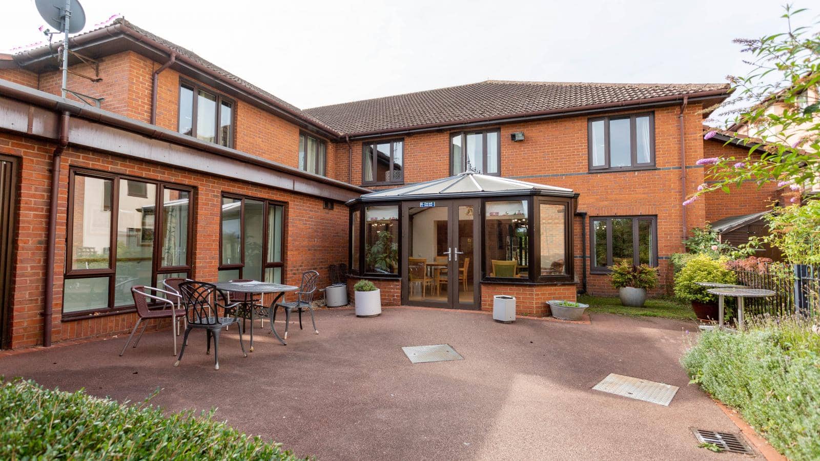 Rear exterior of Westbury Grange care home with a conservatory and patio area