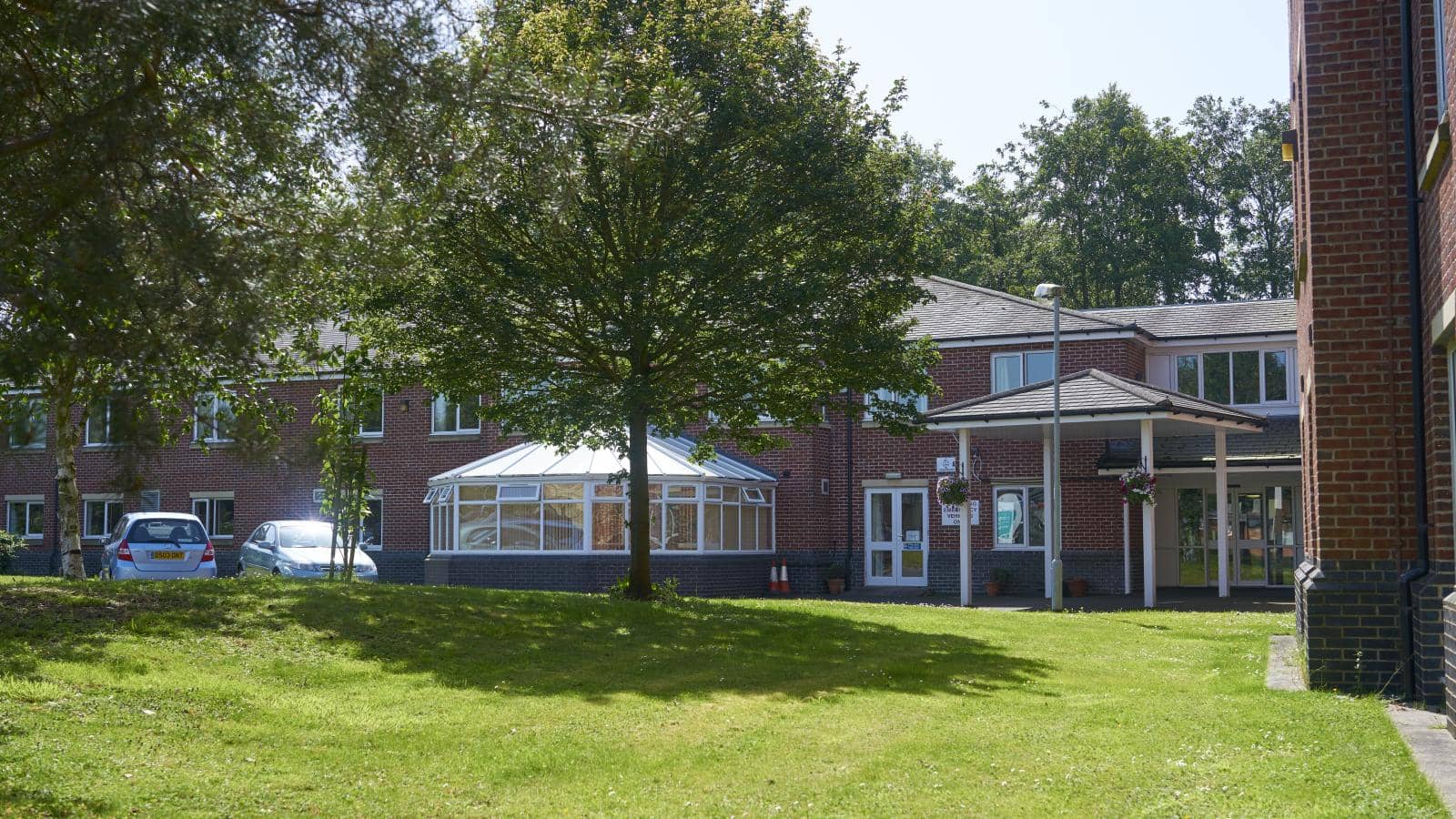 A care home with extensive gardens and a large white conservatory