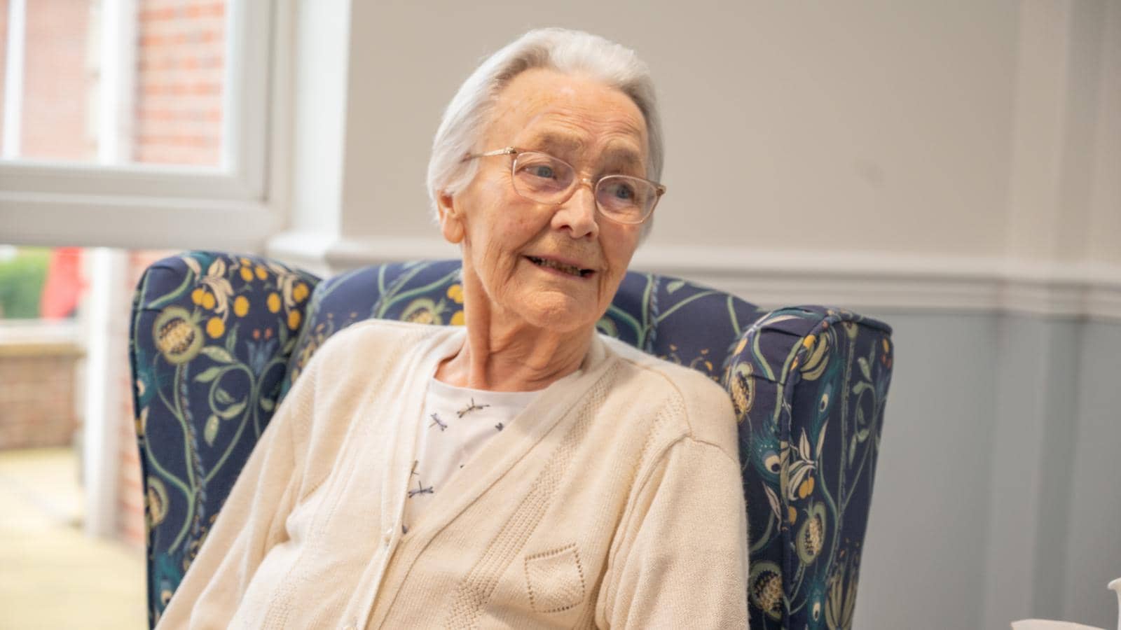 Care home female resident smiling sat in armchair