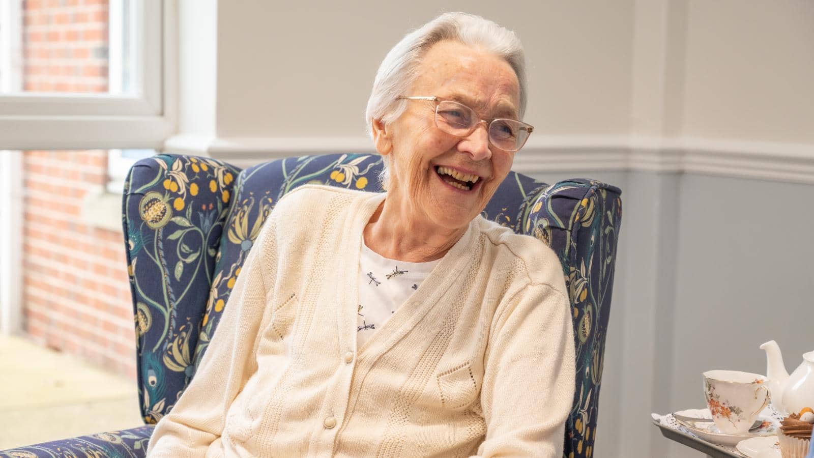 Female resident sat in chair laughing and looking over shoulder