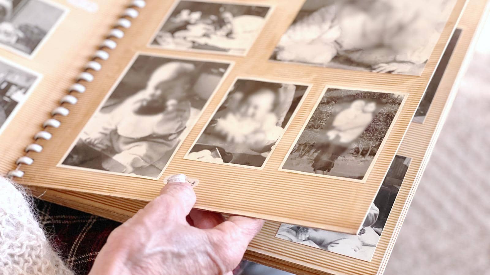 Elderly woman's hand looking at black and white photo album