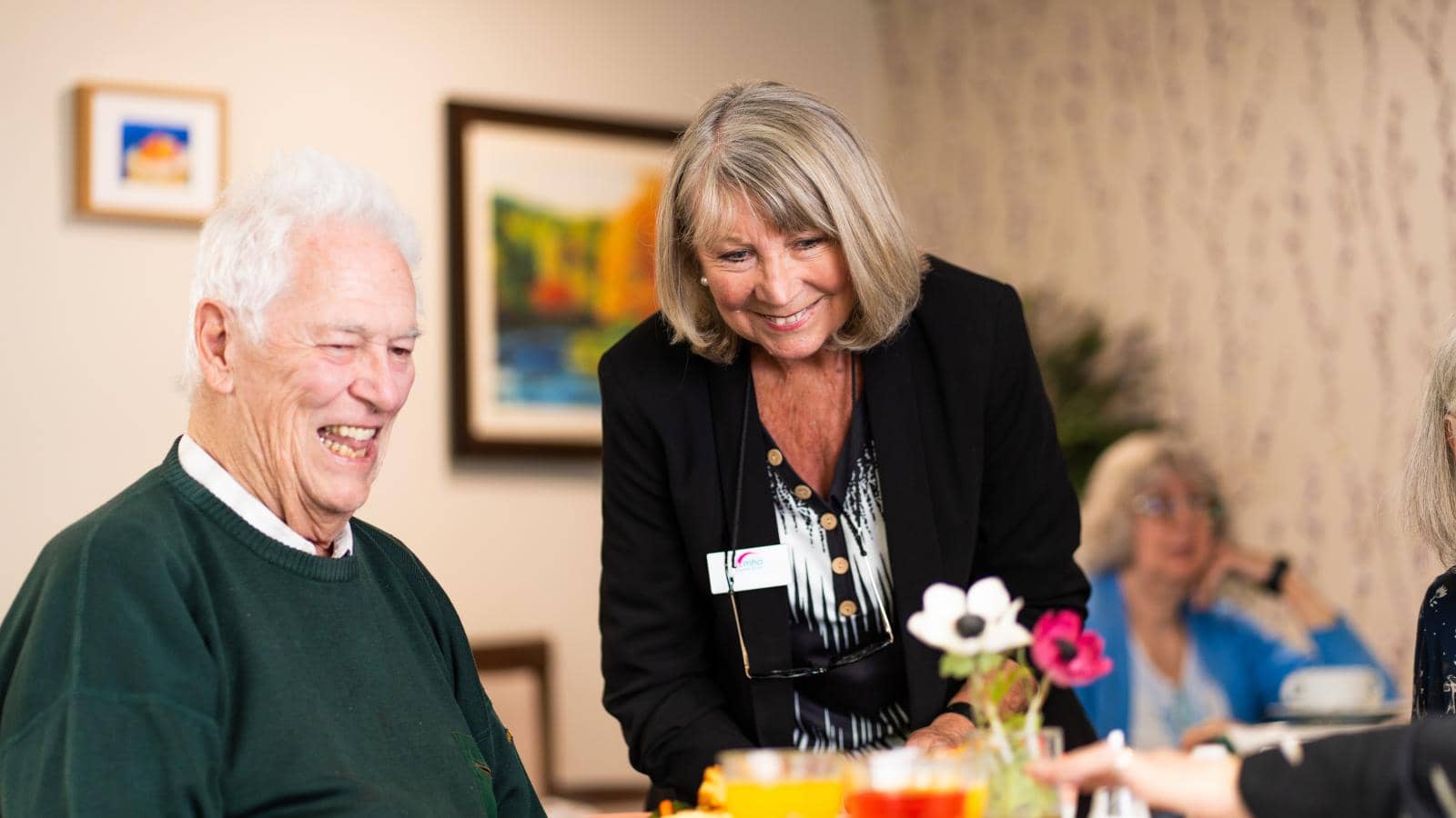 Care home manager speaking to male resident at dining table