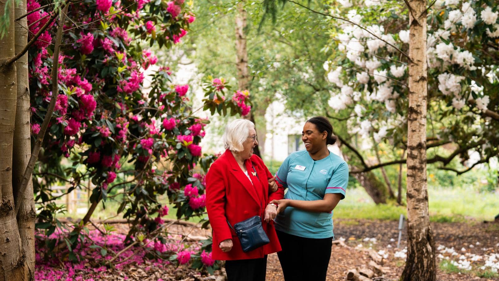 A care worker and an older lady resident walking in the garden