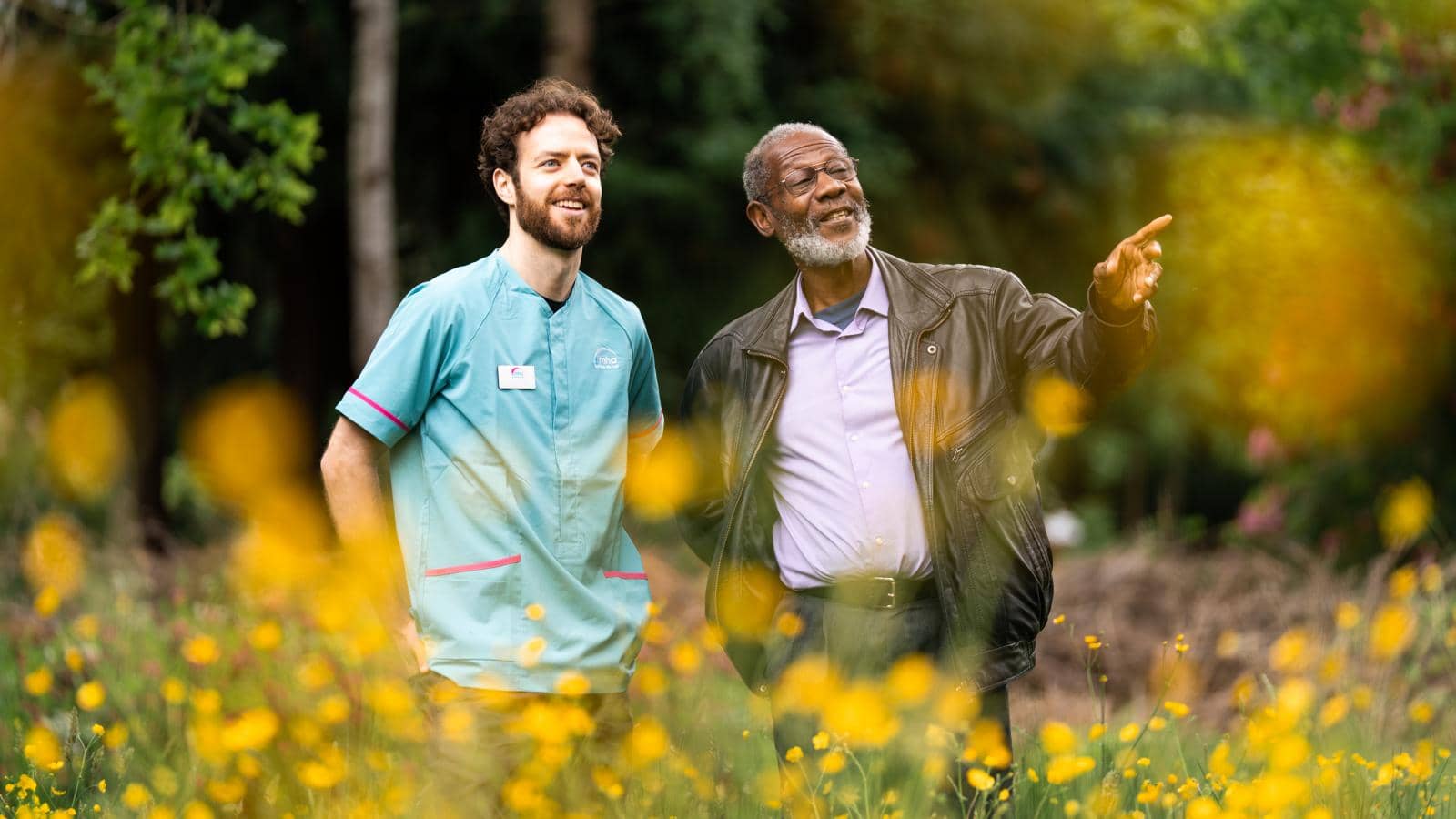 A resident and carer walking through the Wilderness, an extensive MHA garden area situated directly behind Hall Grange.