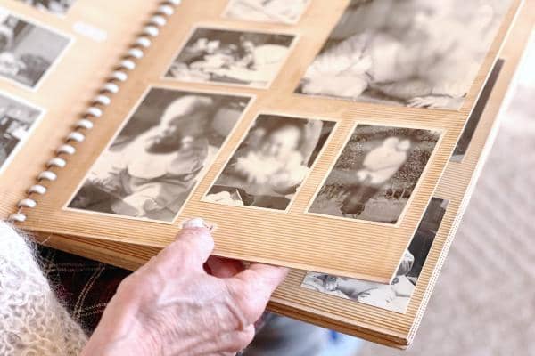 Elderly woman's hand looking at black and white photo album