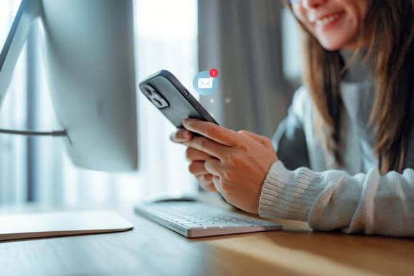 Female hands holding mobile phone with mail icon floating above phone