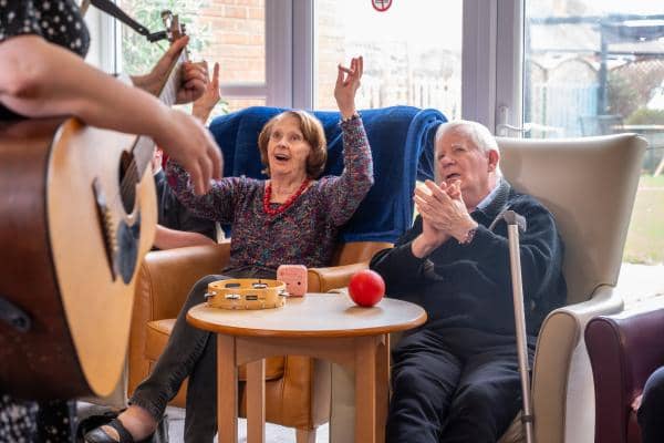 Music therapist playing guitar to male and female care home residents