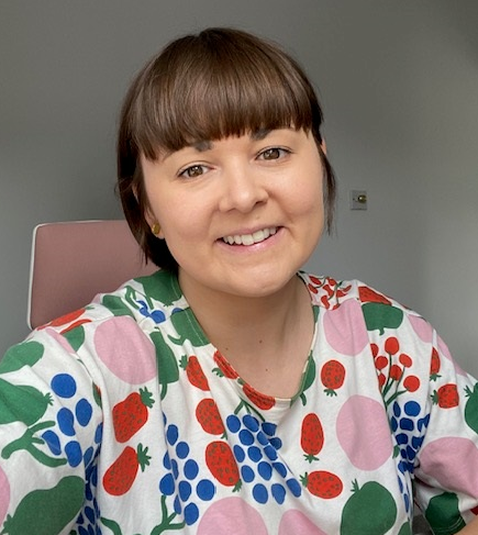 A woman with dark brown hair smiles at the camera 