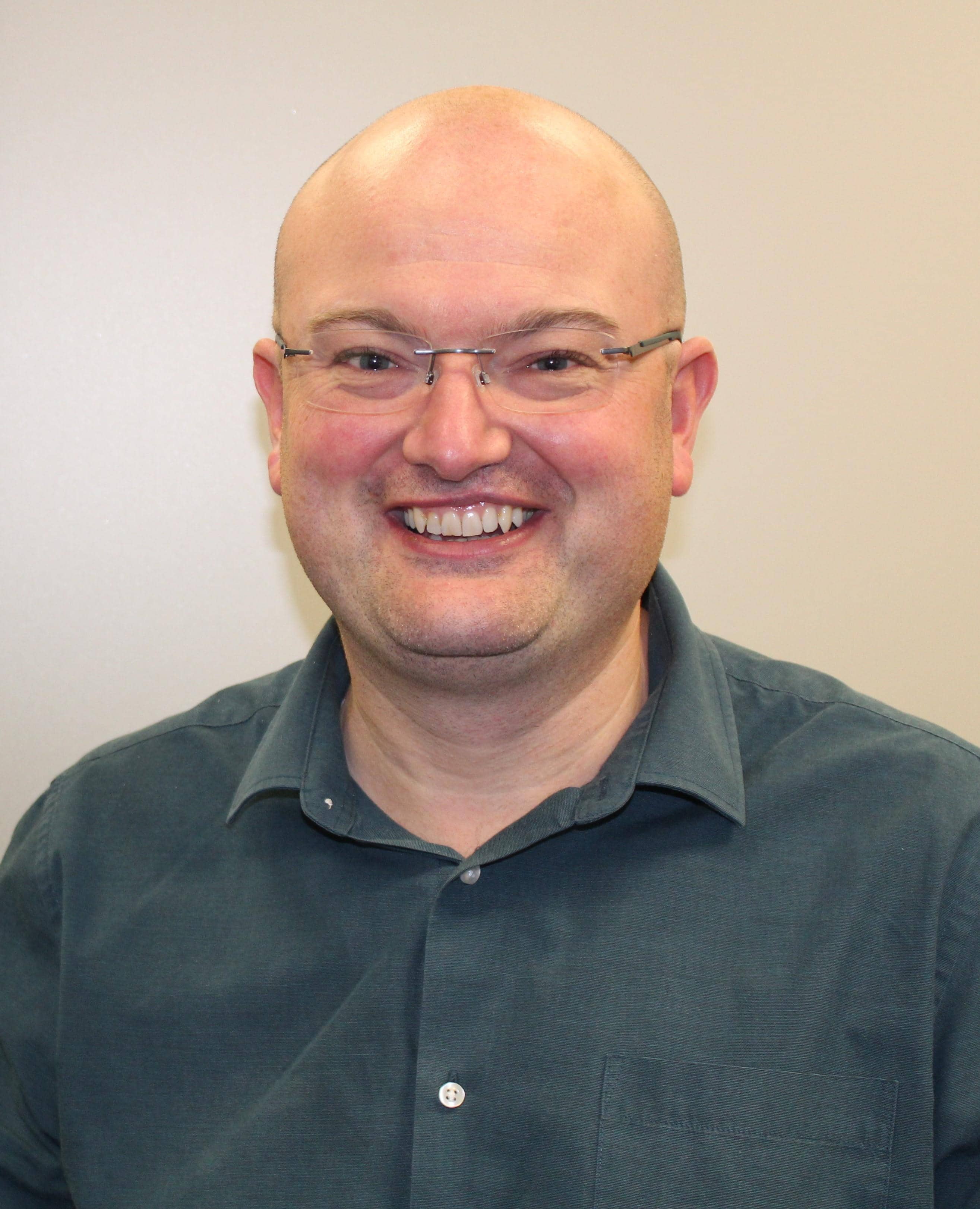 Man with glasses smiles to camera 