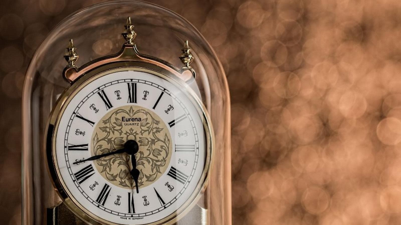 Image focuses in on a traditional clock in a glass cloche