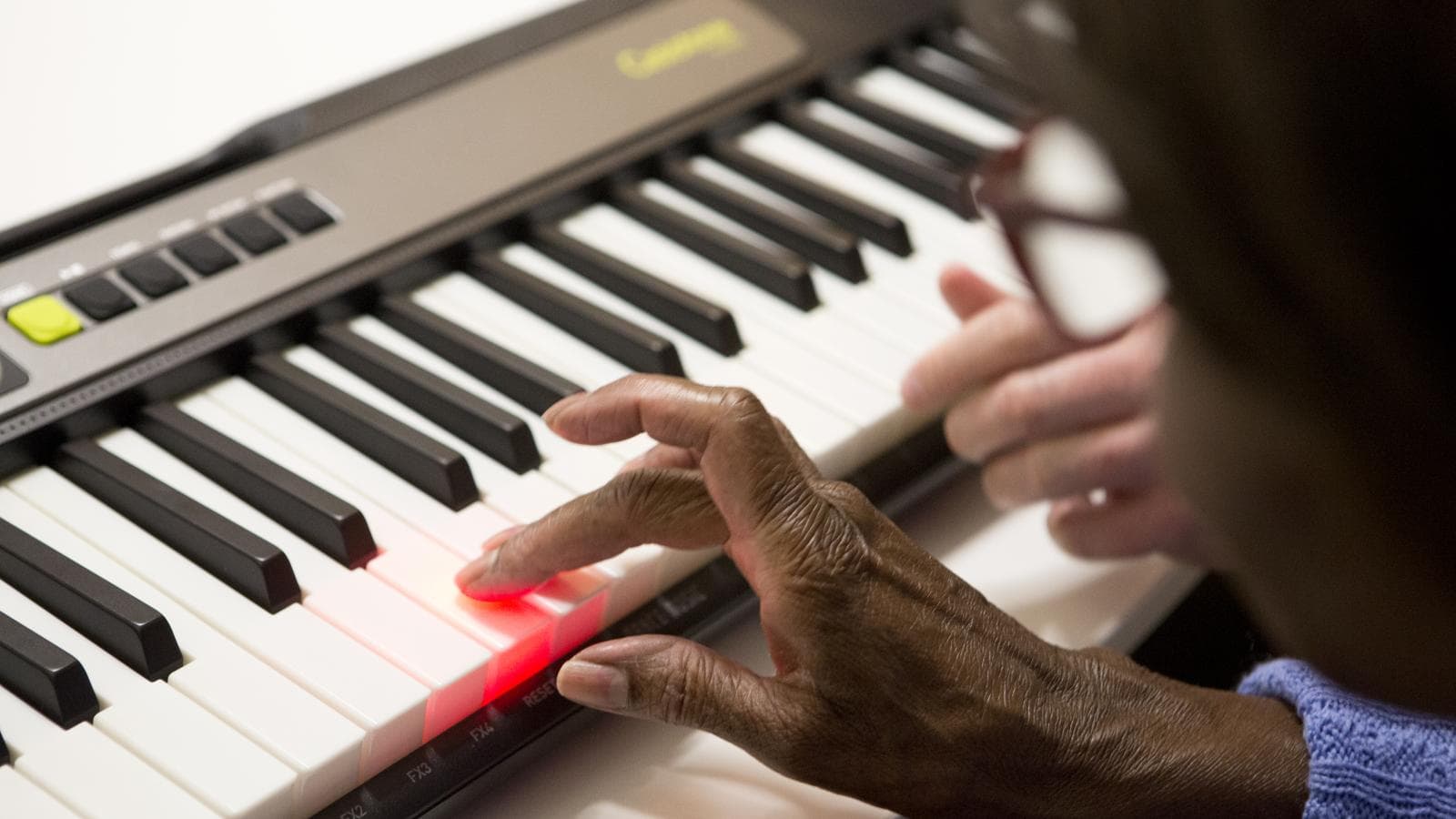Woman plays a note on the Casio keyboard and the key lights up
