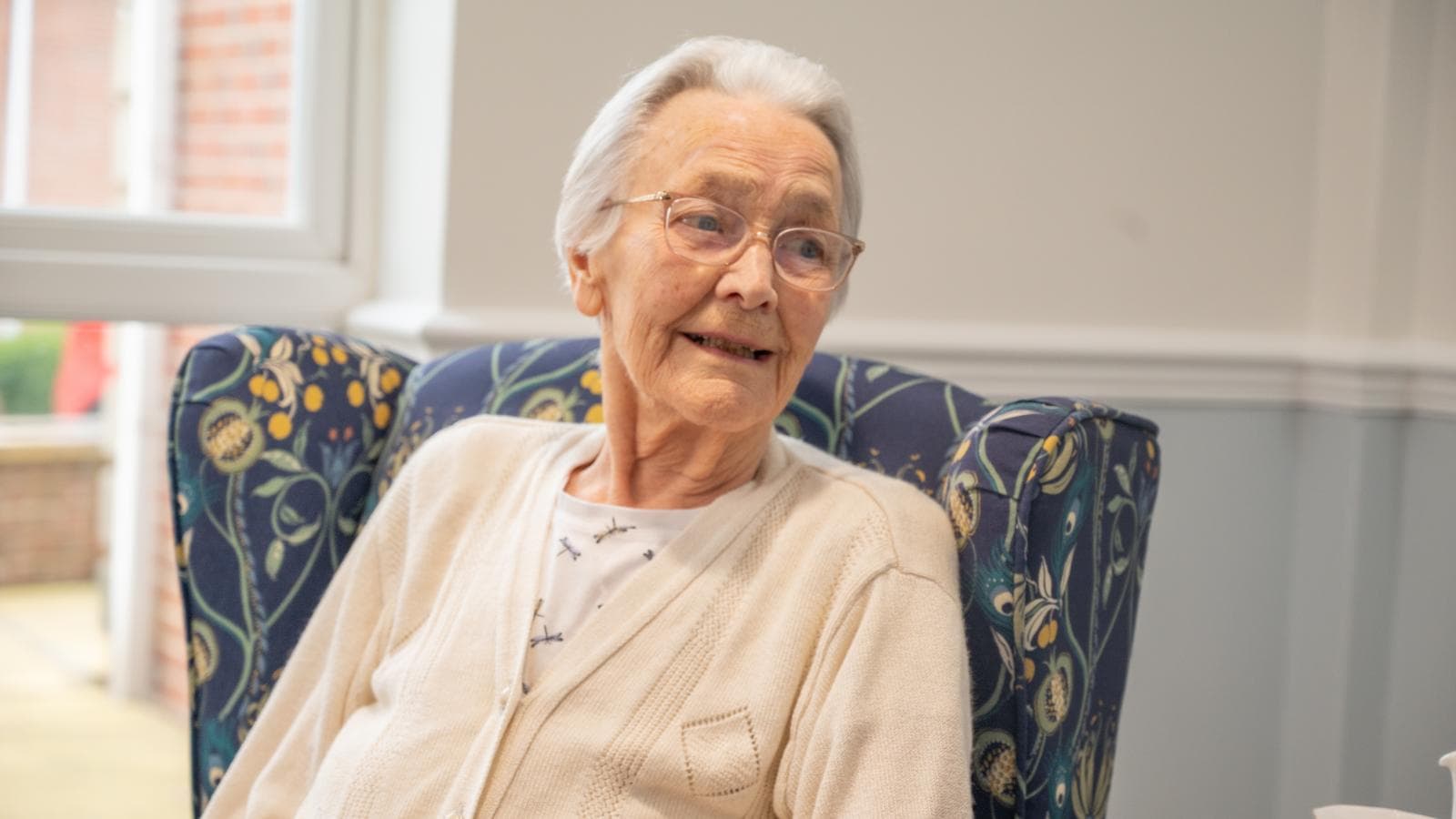 Care home female resident smiling sat in armchair