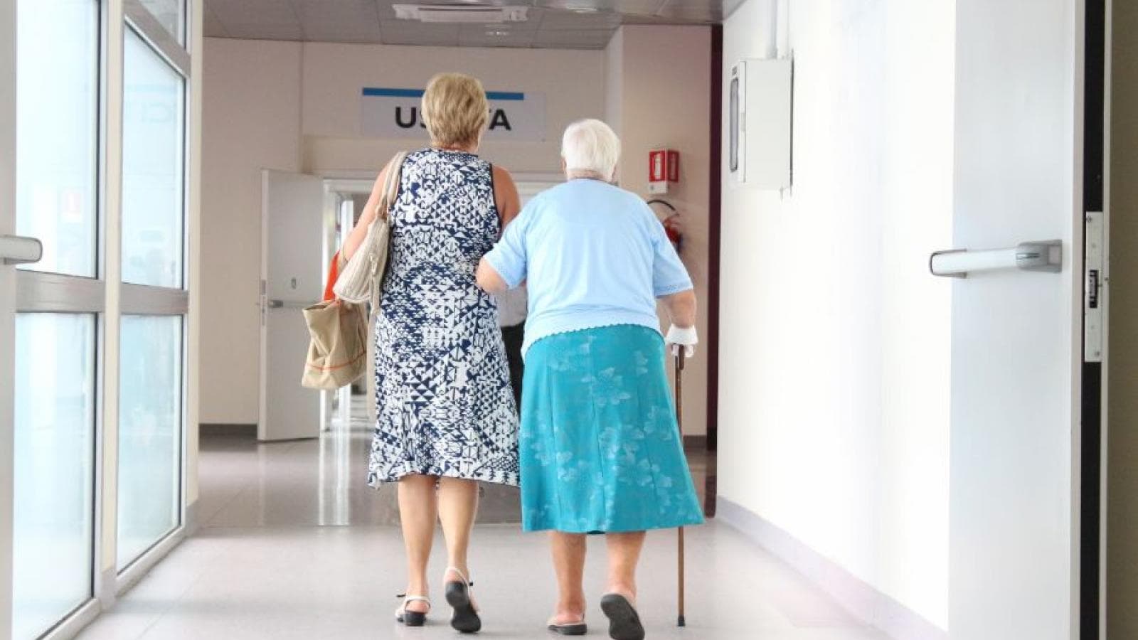 Two women walk down a hospital corridor. 