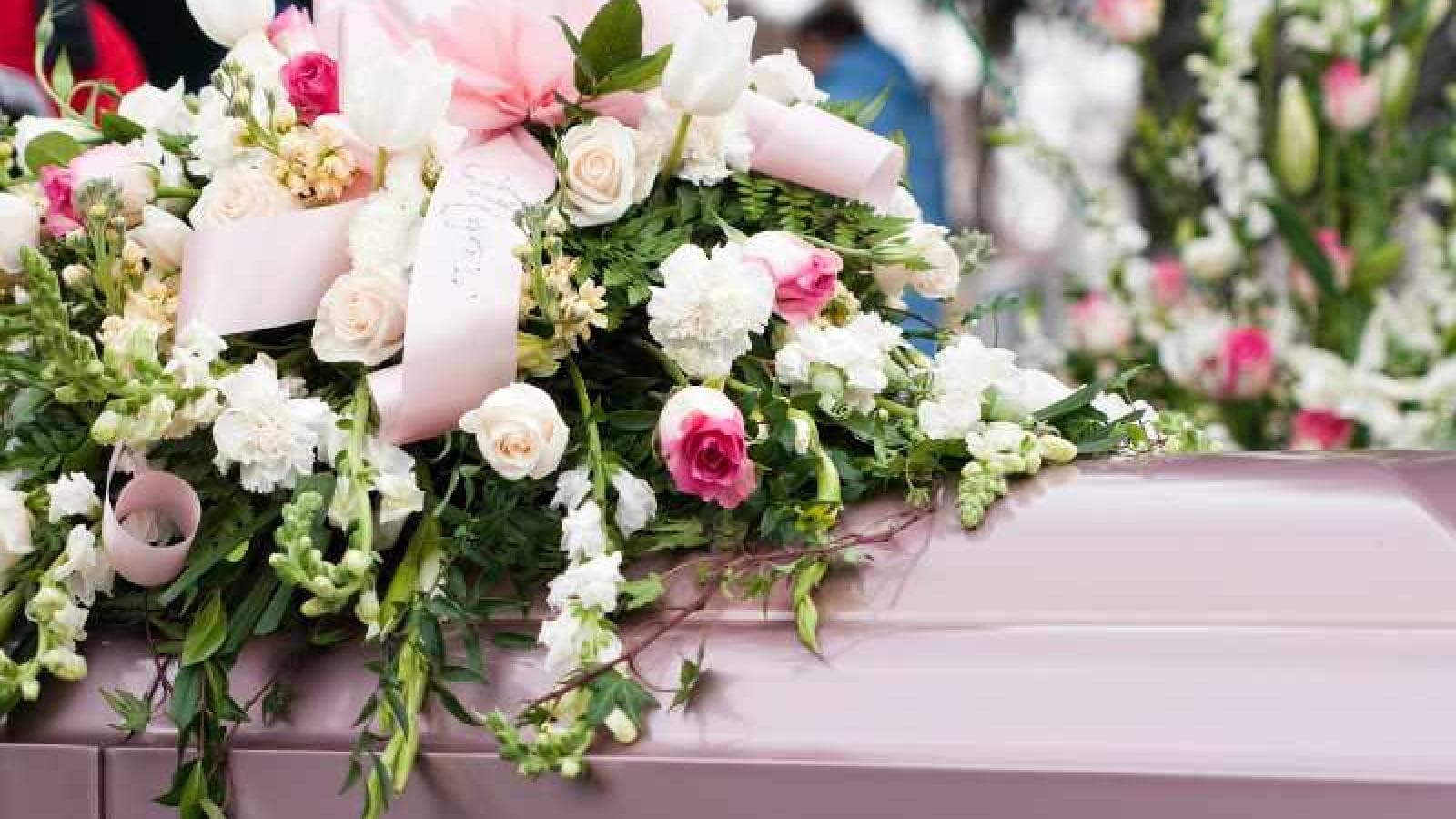 A floral arrangement sits on top of a coffin.