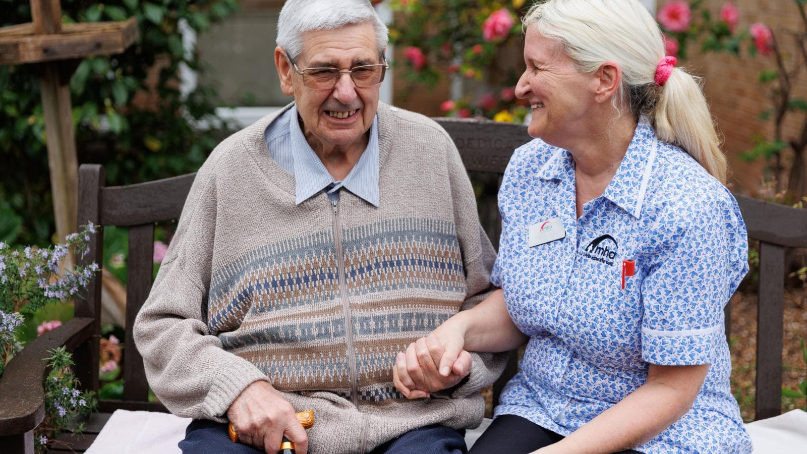 A care assistant sits with a resident in the garden.