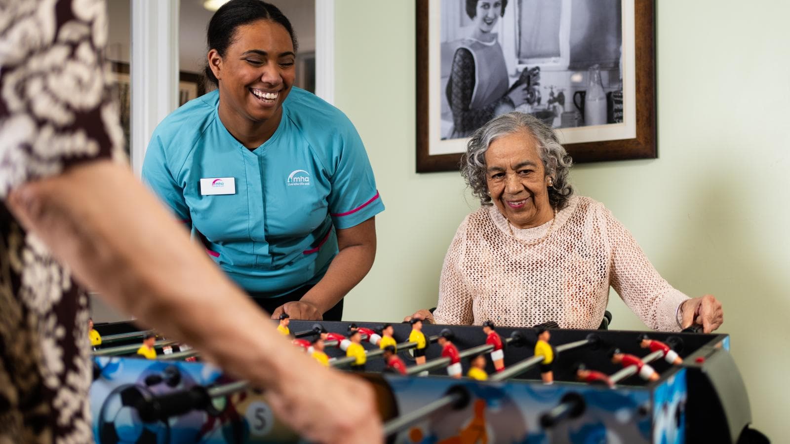 Elderly woman playing table football with a carer