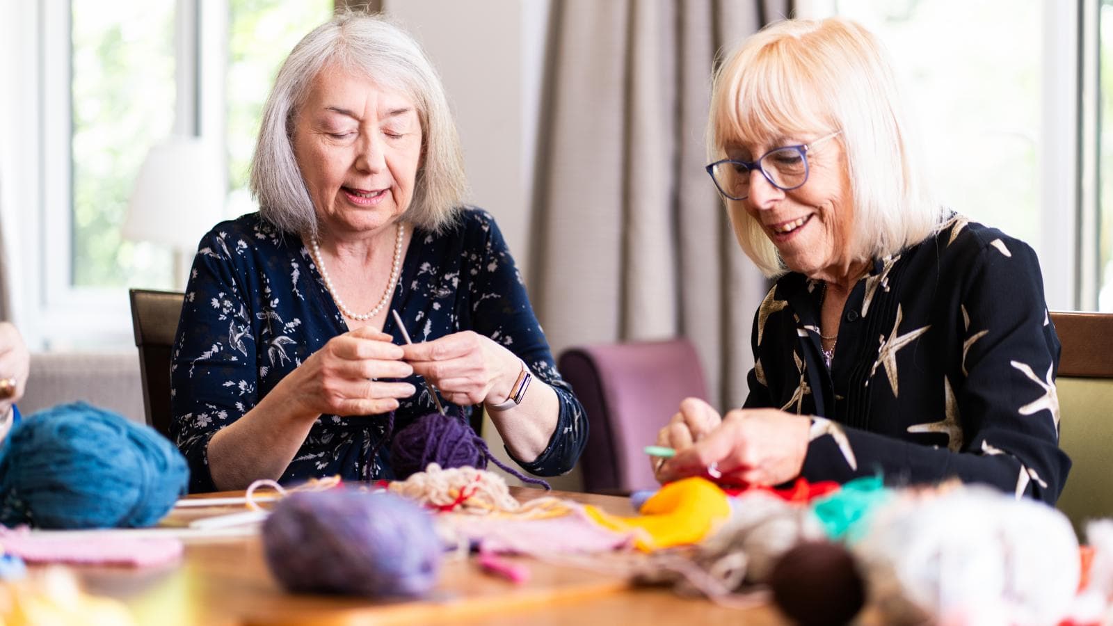 Two older women sat together knitting