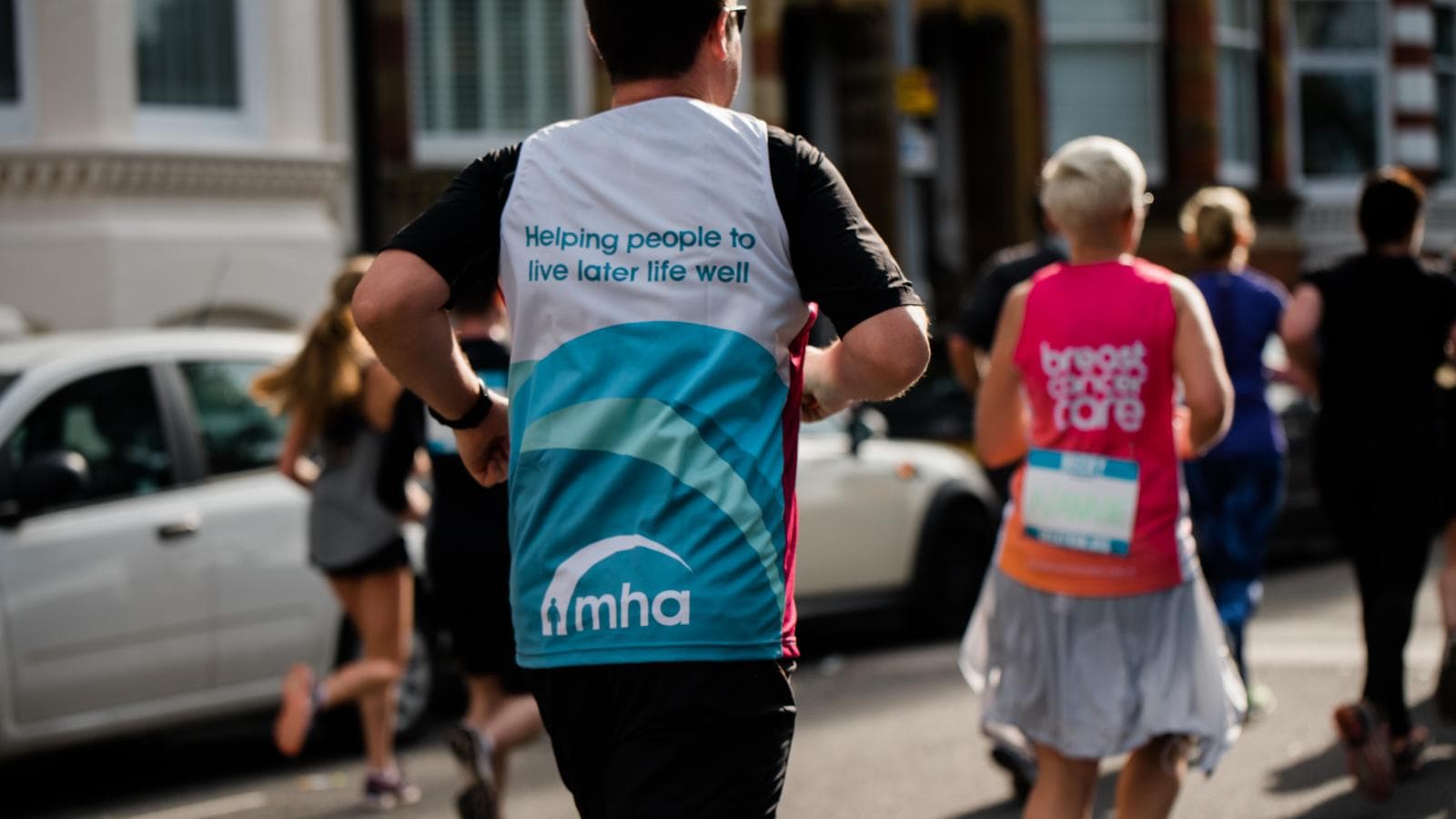 The back of a male runner wearing an MHA fundraising t-shirt