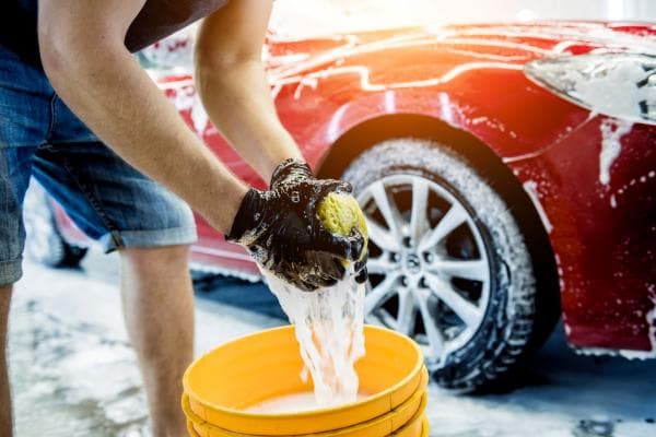 Worker washing red car with sponge on a charity car wash