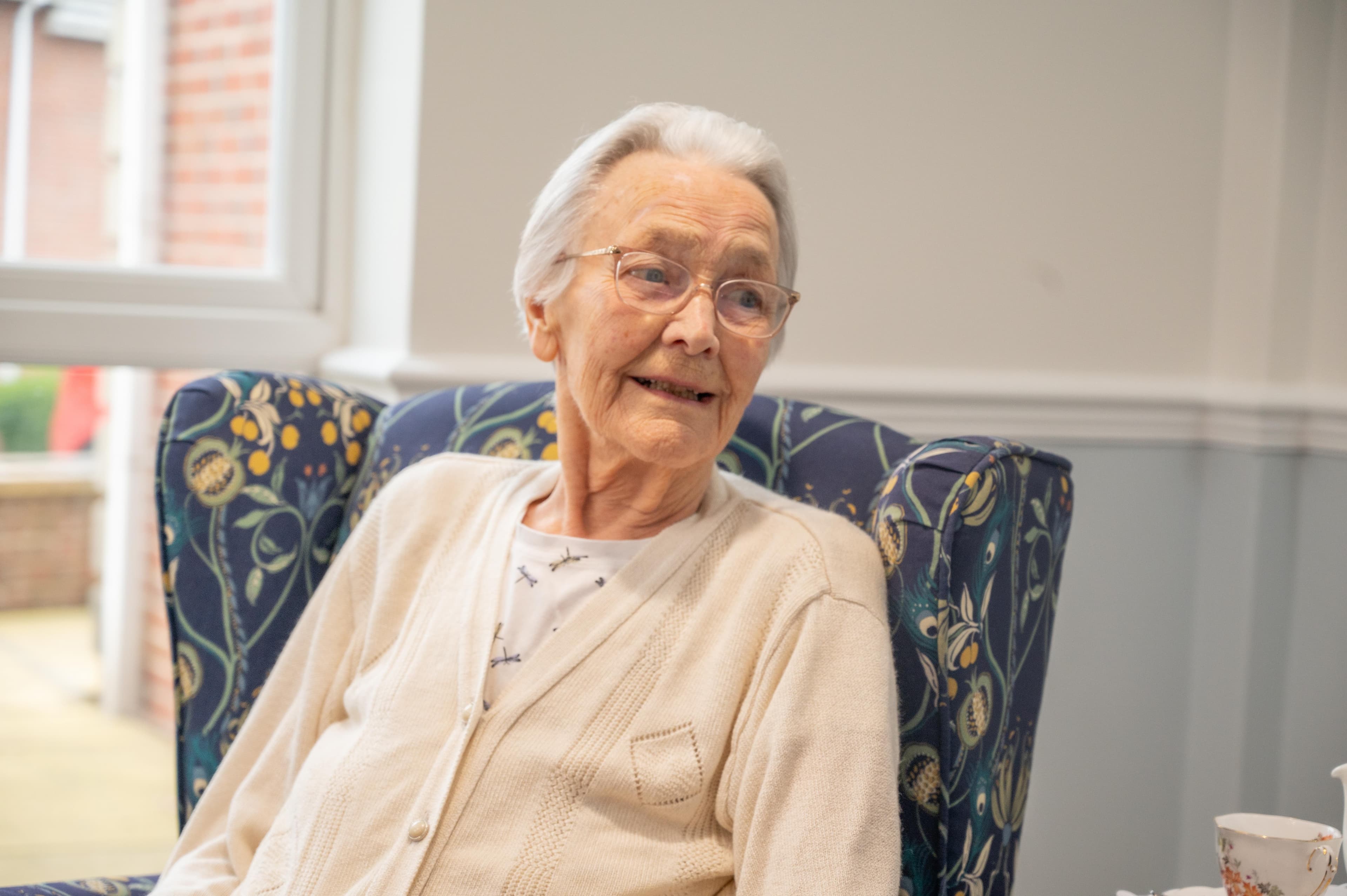 Care home female resident smiling sat in armchair