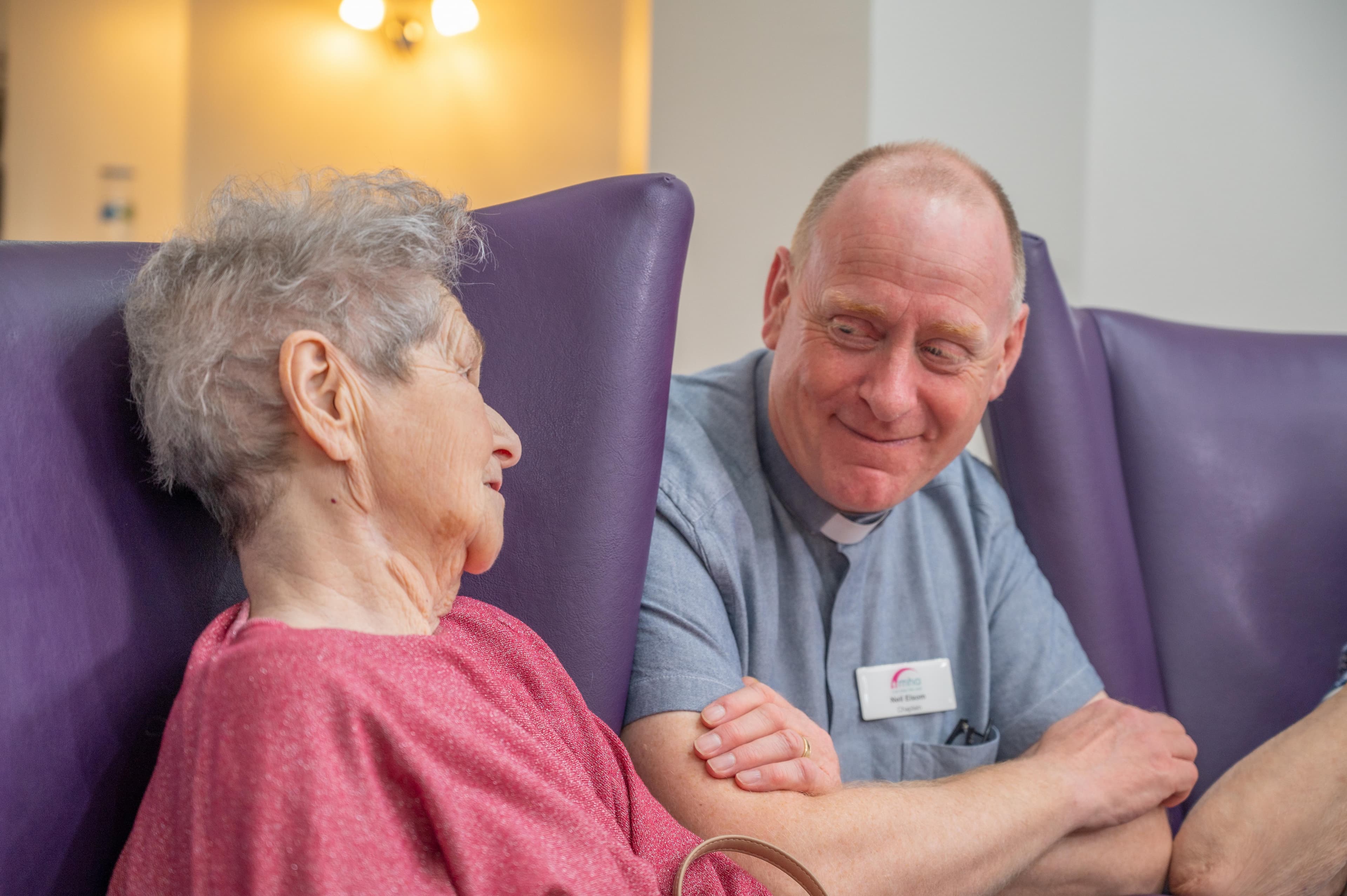 Male MHA chaplain smiling at female care home resident