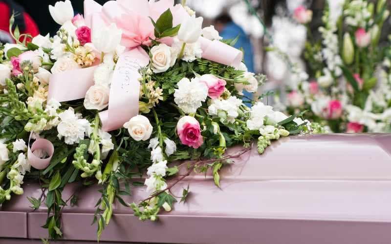 A floral arrangement sits on top of a coffin.