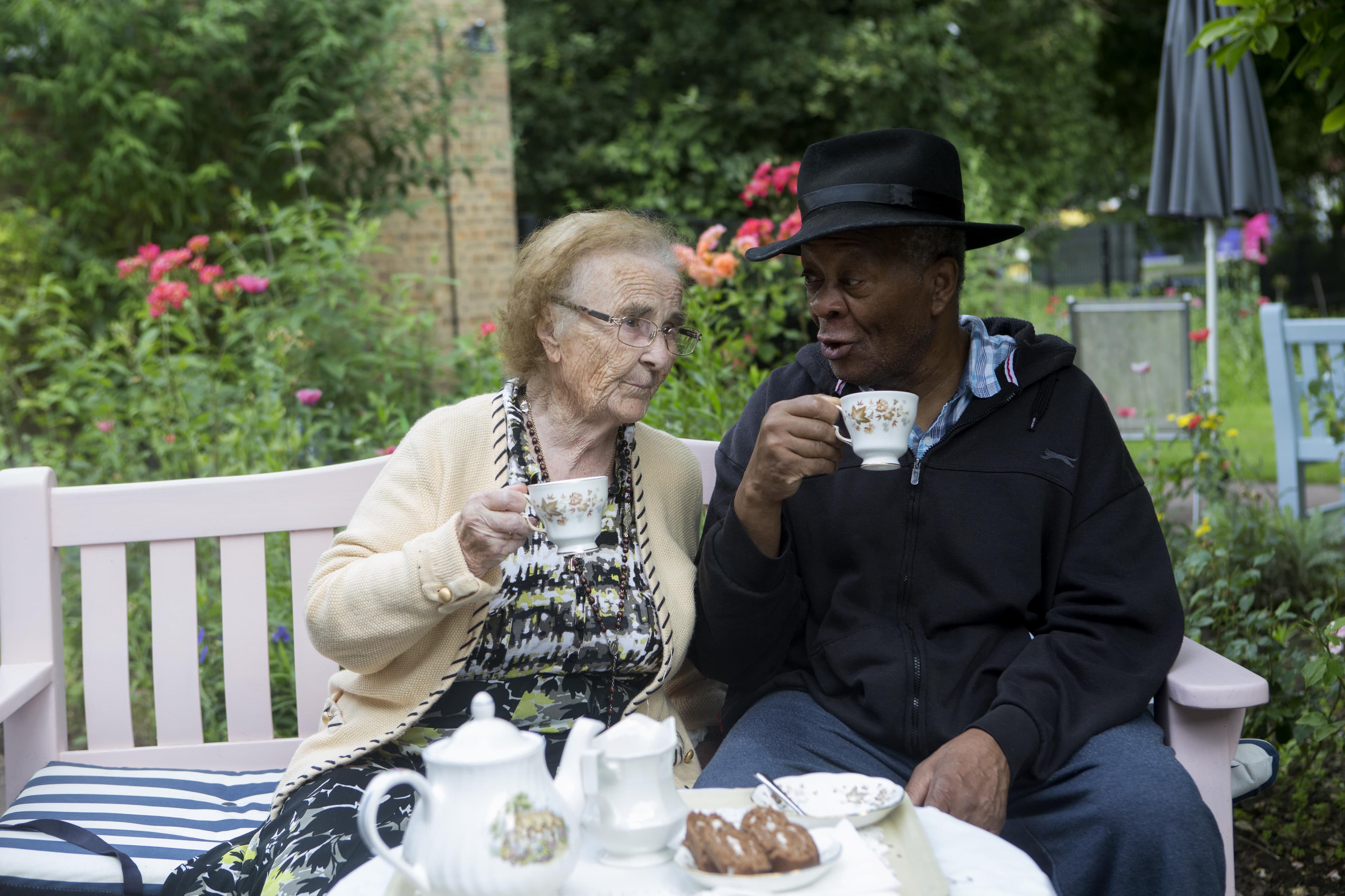 Two residents have a cup of tea in the garden