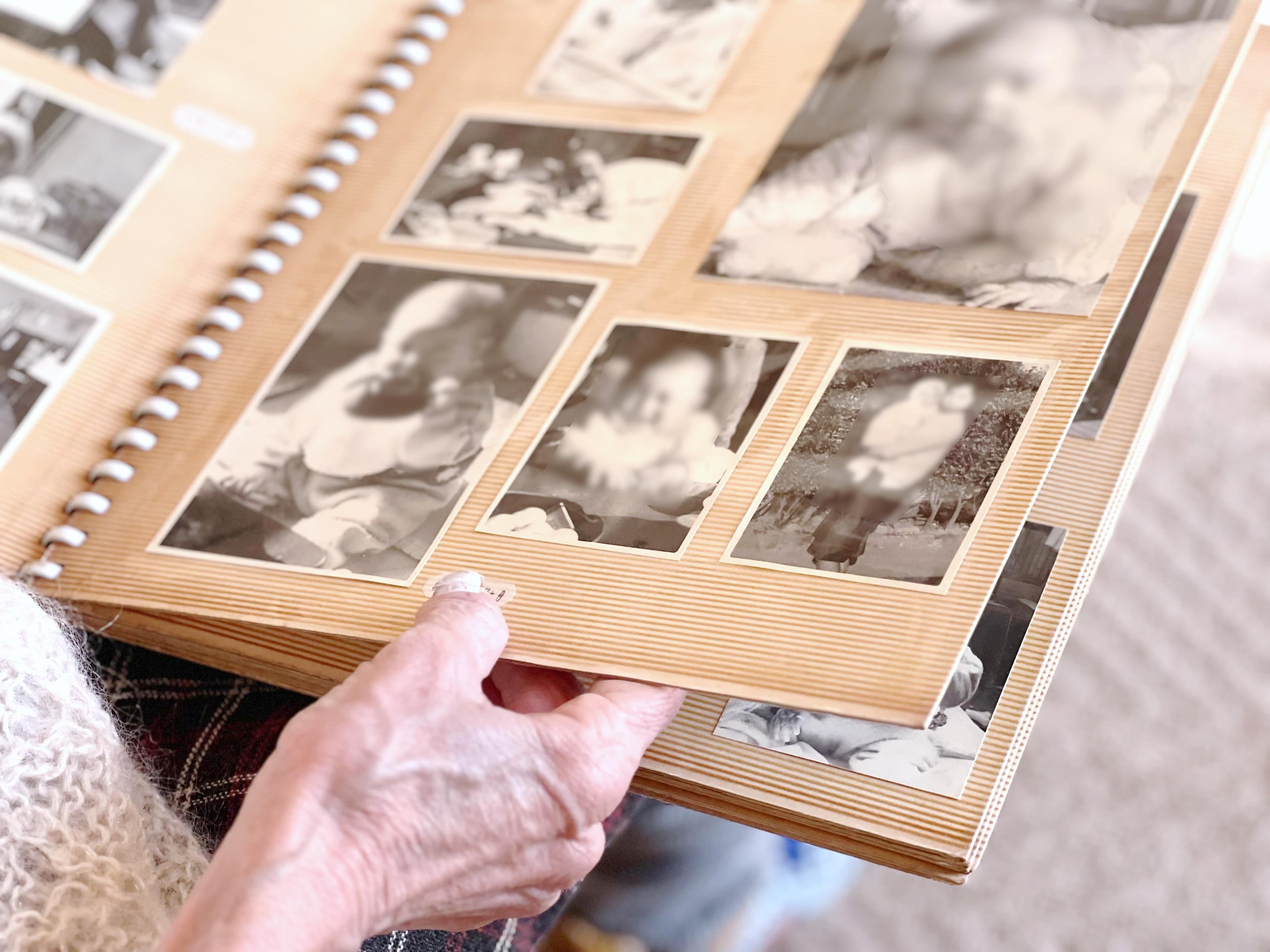Elderly woman's hand looking at black and white photo album