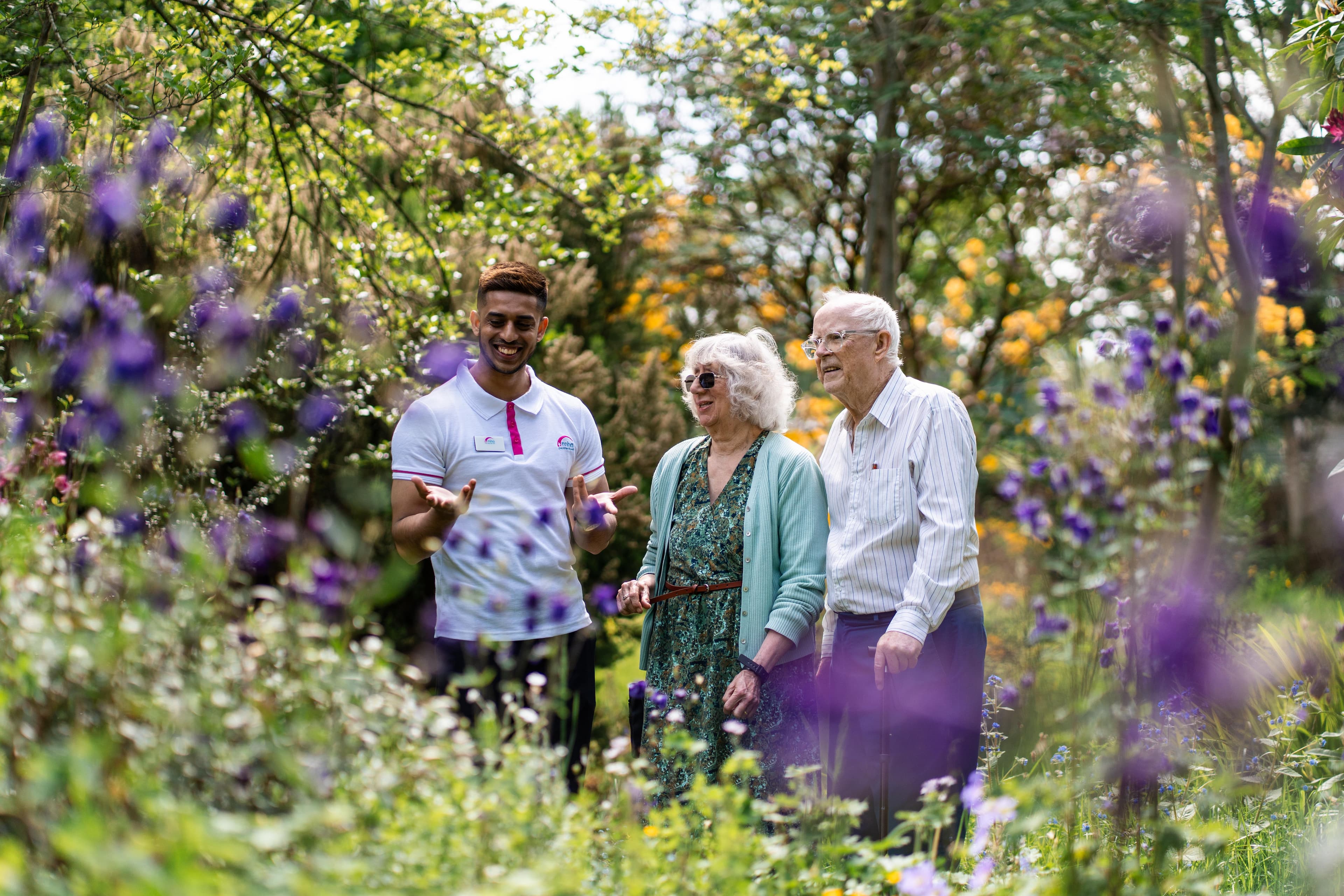 Elderly couple stood with younger man in a garden looking at the flowers together