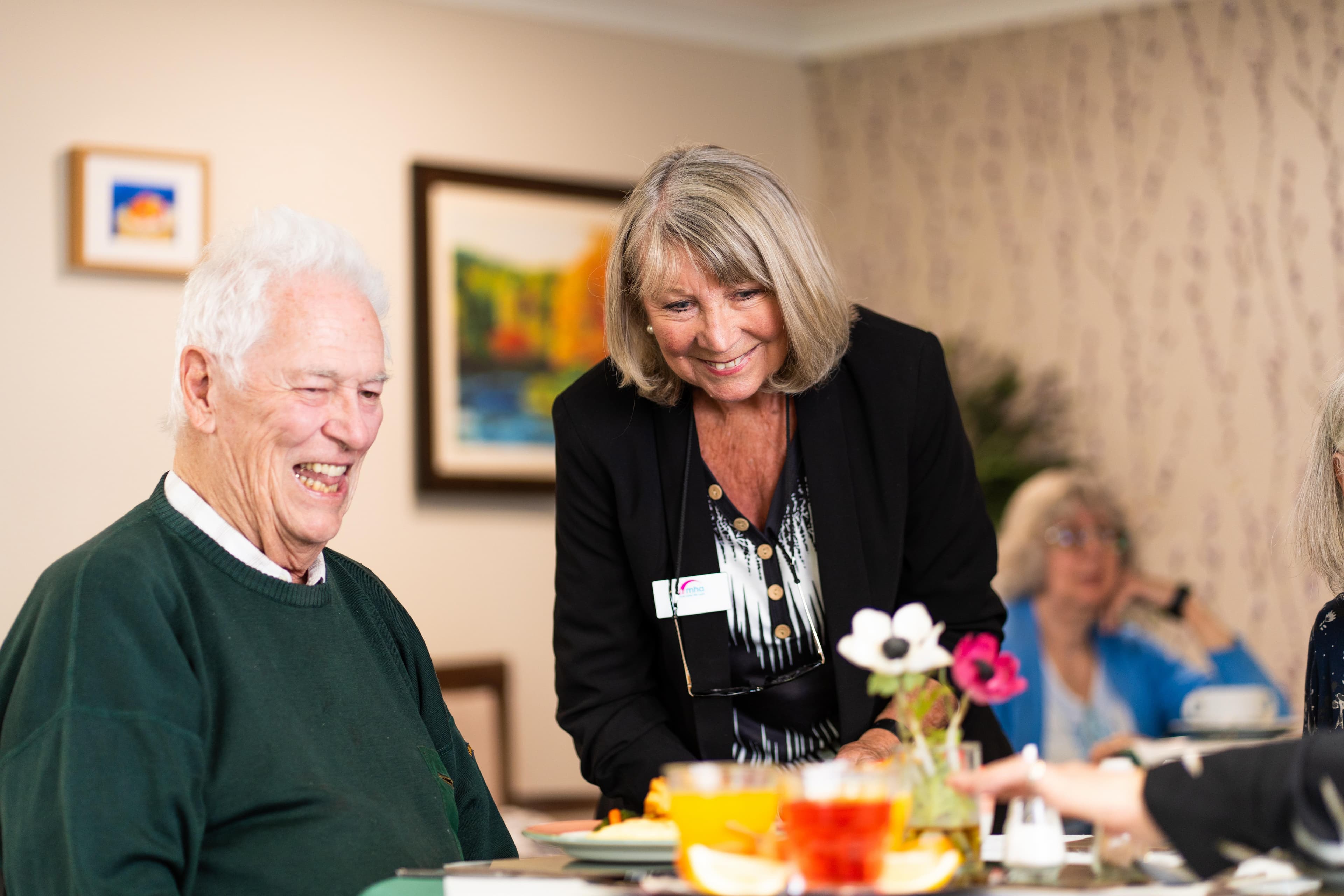 Care home manager speaking to male resident at dining table